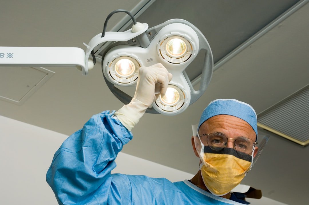 a-man-in-a-surgical-gown-holding-up-a-surgical-light-knsyar6rsug